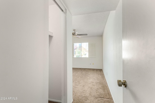 corridor with a textured ceiling and carpet floors