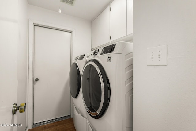 clothes washing area with cabinets, washing machine and dryer, and dark hardwood / wood-style floors