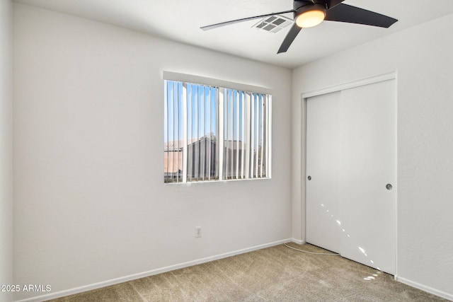 unfurnished bedroom featuring carpet floors, a closet, and ceiling fan