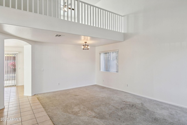 tiled spare room featuring a high ceiling