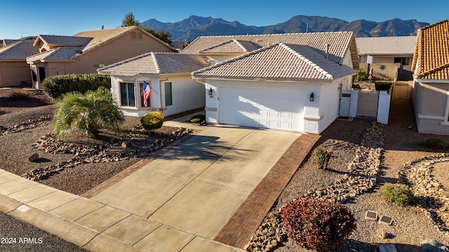 view of front of house with a garage, a mountain view, driveway, and a tile roof
