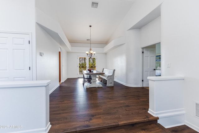 dining space with a notable chandelier, dark hardwood / wood-style floors, and a tray ceiling