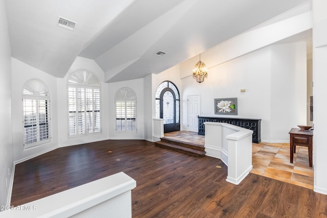 unfurnished living room featuring lofted ceiling, a chandelier, and wood-type flooring