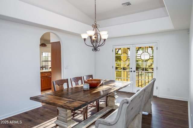 dining area featuring dark wood-type flooring, french doors, an inviting chandelier, and plenty of natural light