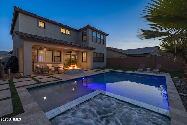 pool at dusk with an outdoor fire pit, a patio area, and ceiling fan