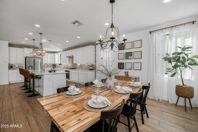 dining room with light hardwood / wood-style floors and a notable chandelier