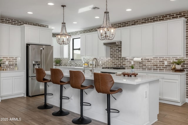 kitchen featuring a center island with sink, white cabinets, and high end refrigerator