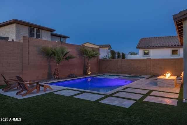 pool at dusk featuring a jacuzzi, a patio area, a yard, and an outdoor fire pit