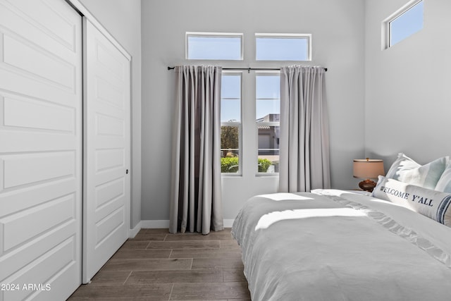 bedroom featuring a closet, dark hardwood / wood-style flooring, and multiple windows