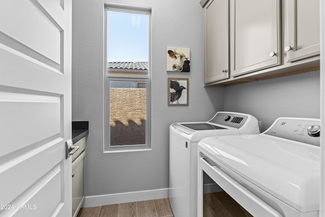 washroom featuring washer and dryer, hardwood / wood-style floors, and cabinets