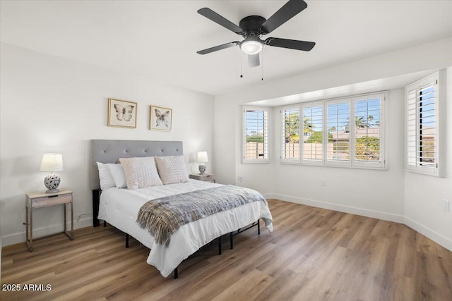 bedroom with ceiling fan, wood finished floors, and baseboards