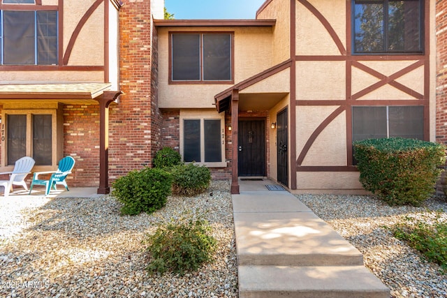 entrance to property featuring a patio area, a chimney, and stucco siding