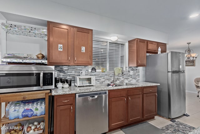 kitchen featuring tasteful backsplash, stainless steel appliances, light tile floors, sink, and a chandelier