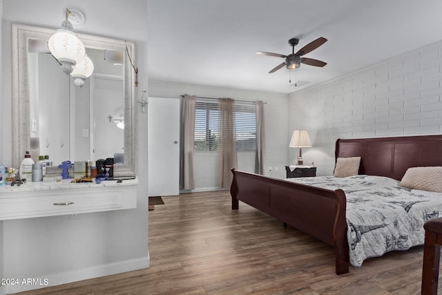 bedroom with ceiling fan, brick wall, and dark hardwood / wood-style floors