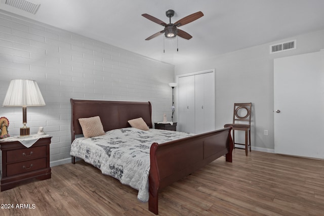 bedroom with a closet, brick wall, ceiling fan, and dark hardwood / wood-style flooring