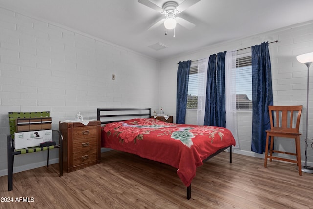 bedroom with hardwood / wood-style floors, brick wall, and ceiling fan