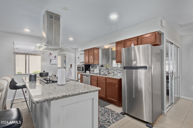 kitchen with a kitchen breakfast bar, fume extractor, stainless steel appliances, light tile floors, and tasteful backsplash