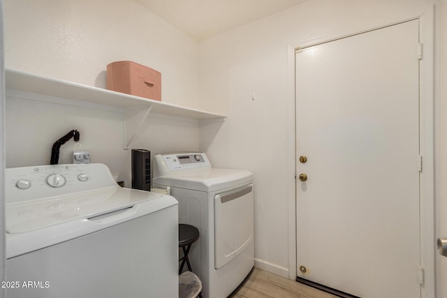 washroom with light wood-type flooring, laundry area, baseboards, and washer and dryer