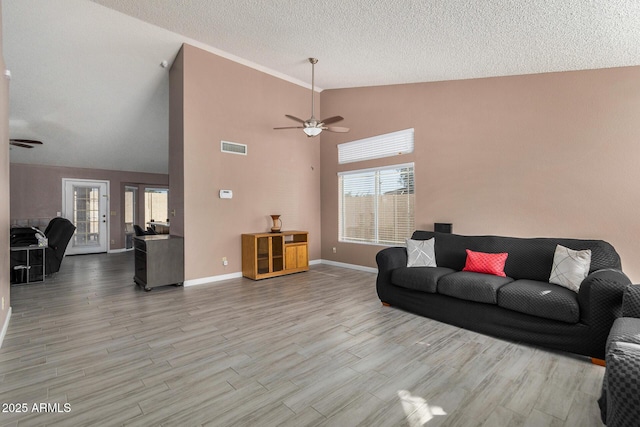 living area with a textured ceiling, wood finished floors, visible vents, and a healthy amount of sunlight