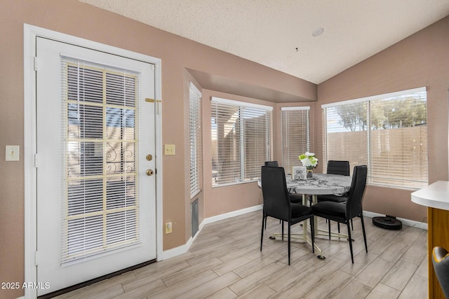 dining area featuring wood tiled floor, baseboards, and vaulted ceiling