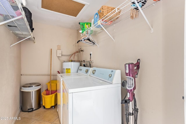 laundry area featuring washer and dryer, light tile patterned flooring, and water heater