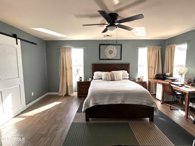 bedroom featuring ceiling fan, dark wood-type flooring, and a barn door