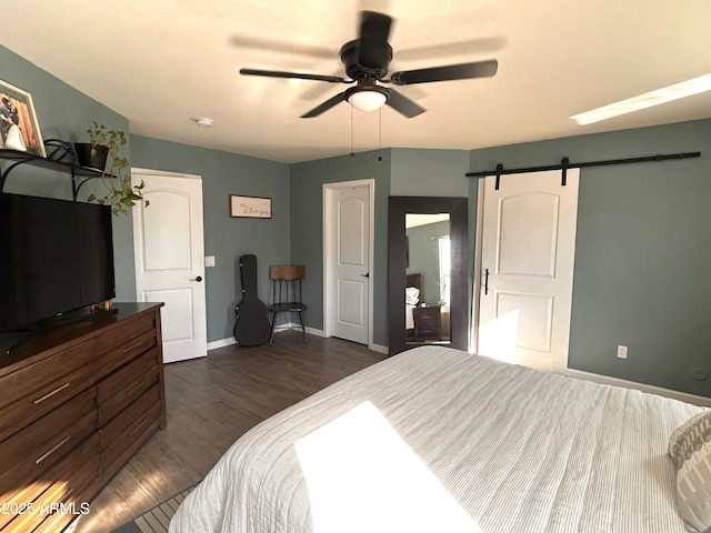 bedroom with ceiling fan, a barn door, and dark hardwood / wood-style floors