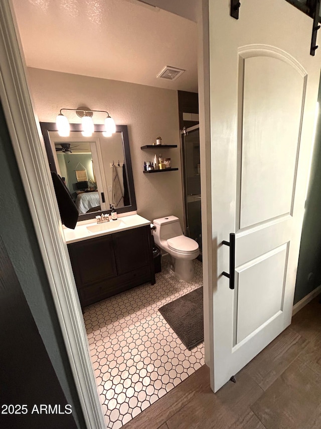 bathroom featuring toilet, an enclosed shower, ceiling fan, and vanity