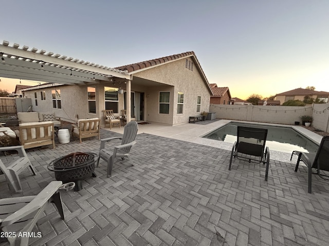 patio terrace at dusk with an outdoor living space with a fire pit and a fenced in pool