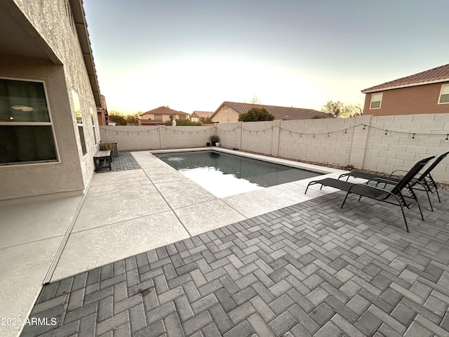 pool at dusk featuring a patio area