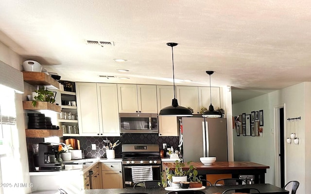 kitchen with sink, decorative light fixtures, backsplash, and appliances with stainless steel finishes