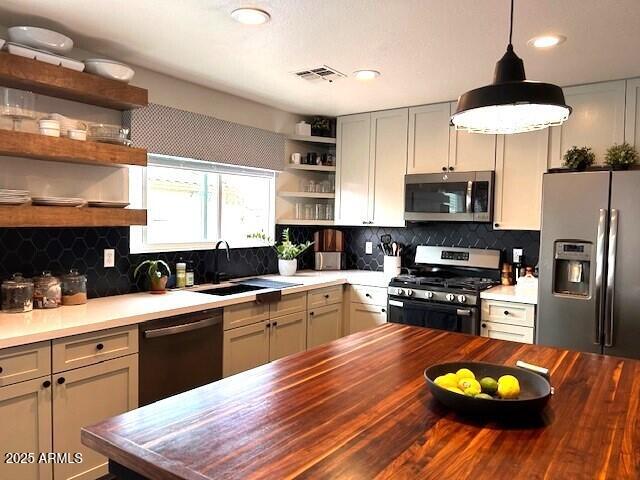 kitchen featuring appliances with stainless steel finishes, butcher block countertops, backsplash, and sink