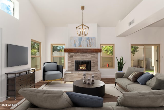 living room featuring hardwood / wood-style flooring, a tile fireplace, a healthy amount of sunlight, and a high ceiling