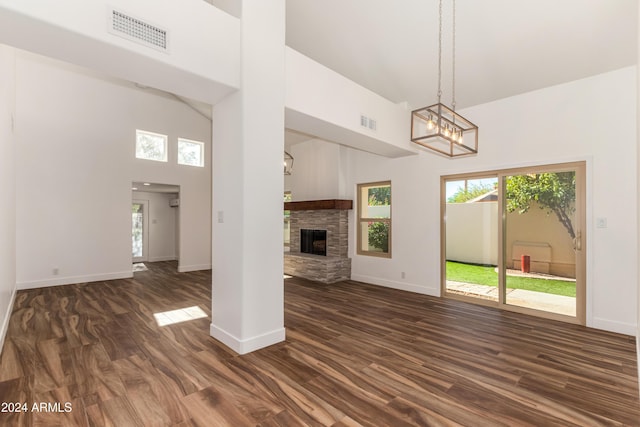 unfurnished living room with a towering ceiling, dark hardwood / wood-style flooring, and a stone fireplace