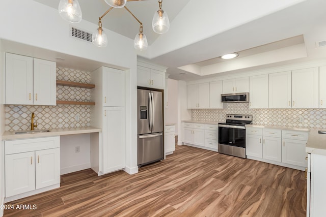 kitchen featuring hardwood / wood-style floors, decorative light fixtures, white cabinetry, sink, and stainless steel appliances