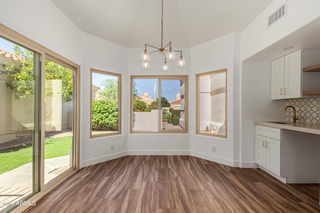 unfurnished dining area featuring dark wood-type flooring, sink, and a notable chandelier