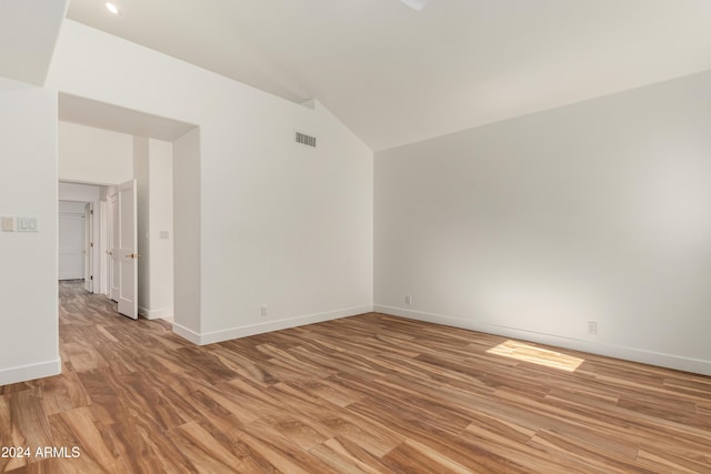 spare room with lofted ceiling and light wood-type flooring