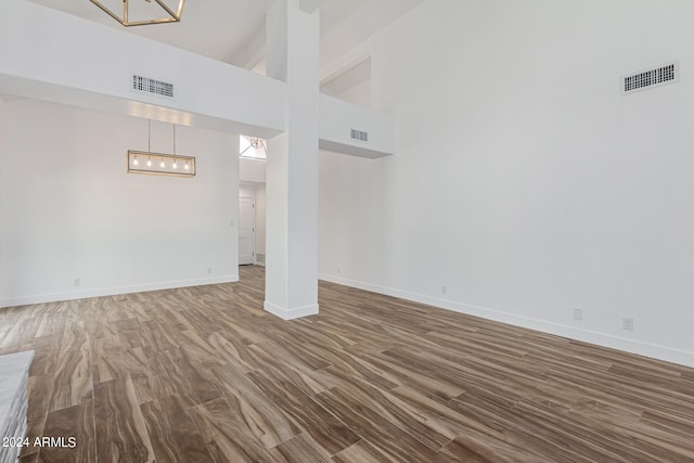 unfurnished living room with a towering ceiling and hardwood / wood-style floors