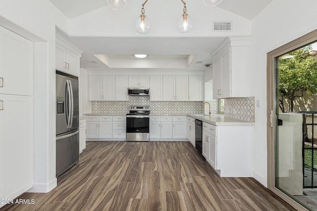 kitchen with appliances with stainless steel finishes, decorative light fixtures, white cabinetry, sink, and dark wood-type flooring