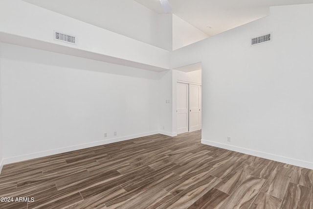 empty room featuring dark hardwood / wood-style flooring and a towering ceiling