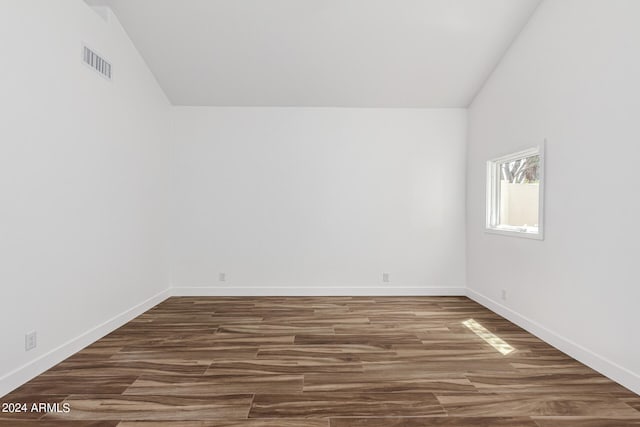 spare room featuring vaulted ceiling and dark hardwood / wood-style flooring