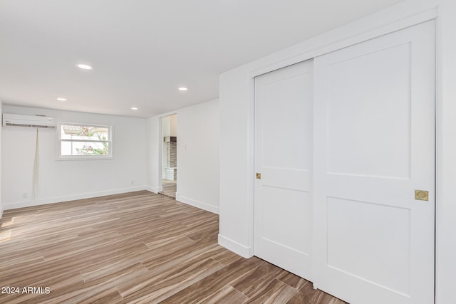 basement featuring light hardwood / wood-style flooring and a wall mounted AC