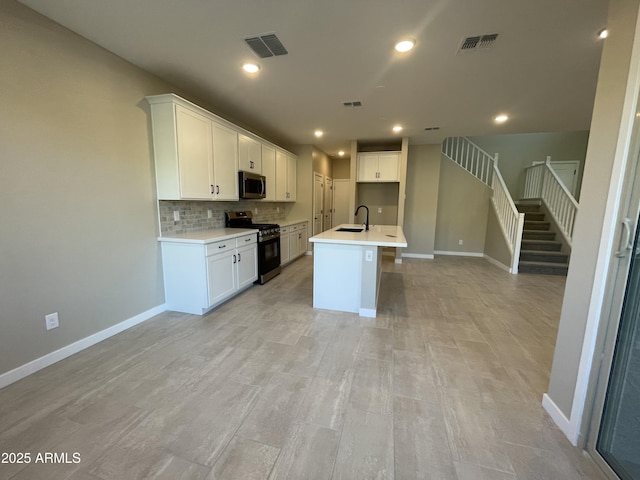 kitchen featuring tasteful backsplash, appliances with stainless steel finishes, a center island with sink, and white cabinets