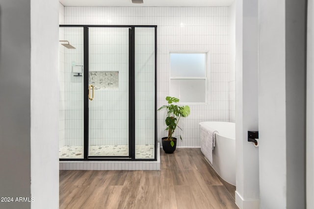 bathroom featuring tile walls, wood-type flooring, and a bathing tub