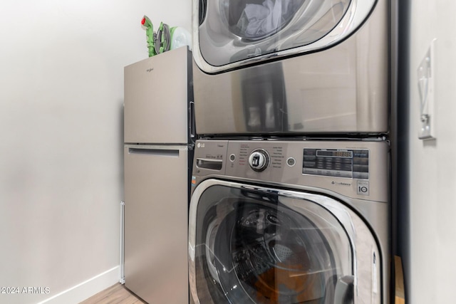 laundry room featuring stacked washer and clothes dryer and light hardwood / wood-style floors