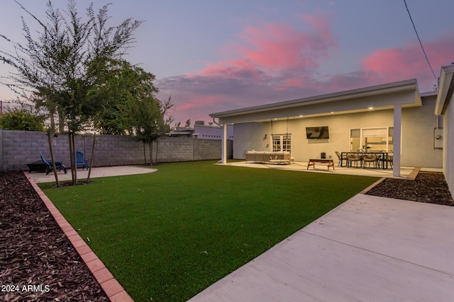 yard at dusk with an outdoor living space and a patio