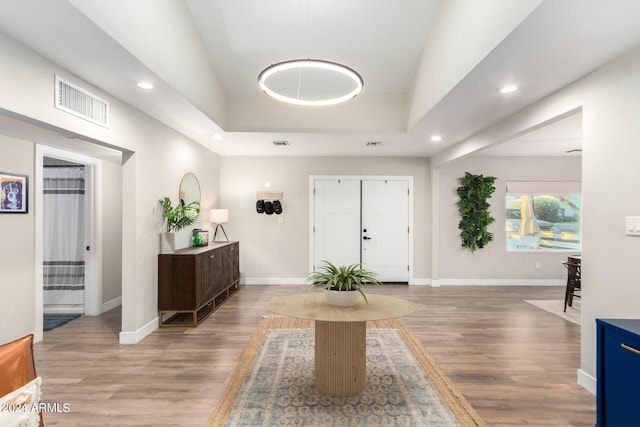 foyer entrance with wood-type flooring and a raised ceiling