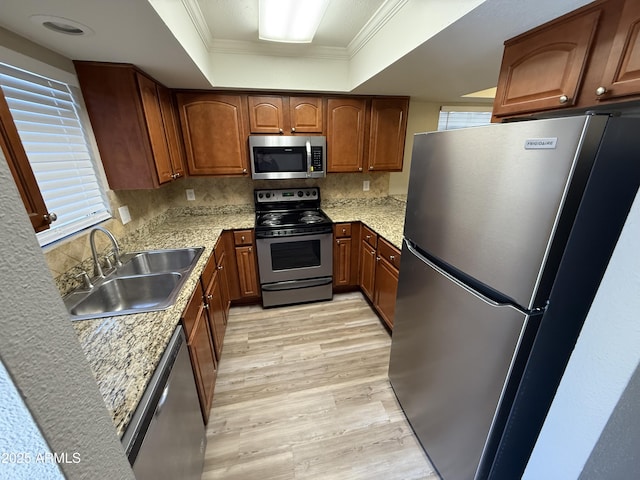 3434 W Danbury Dr Unit A206, Phoenix, AZ 85053 - kitchen with appliances with stainless steel finishes, light wood finished floors, crown molding, a tray ceiling, and decorative backsplash