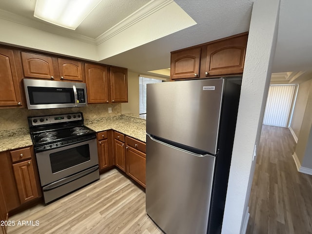 3434 W Danbury Dr Unit A206, Phoenix, AZ 85053 - kitchen featuring stainless steel appliances, light wood-style flooring, ornamental molding, and brown cabinetry