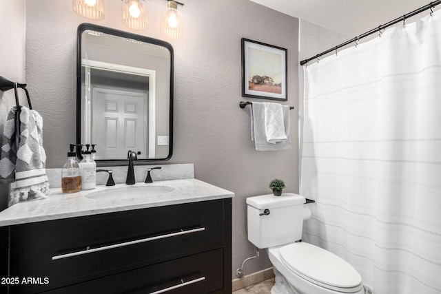 bathroom featuring vanity, toilet, and a textured wall